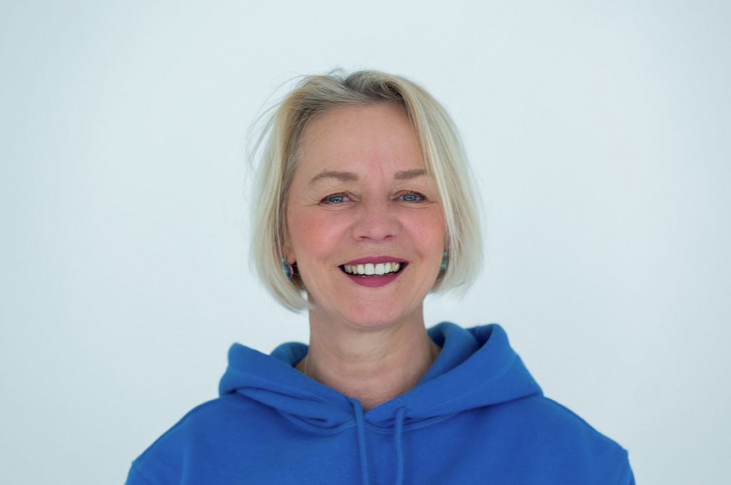 Karin Silies. Frau mit kinnlangen, blonden Haar, in einem blauen Hoody.