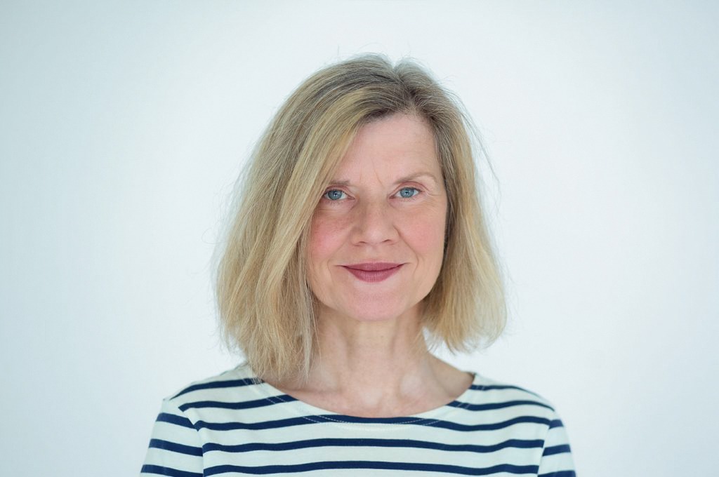 Regina Millhagen. Frau mit schulterlangen, blonden Haar, in einem weiß-schwarz gestreiften Sweater.
